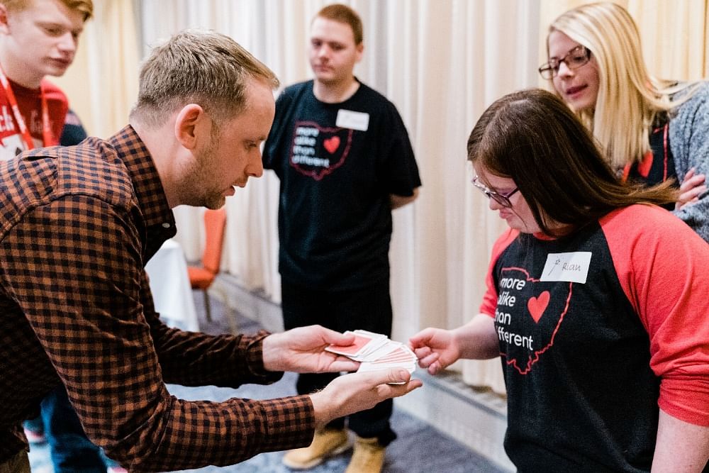 Magician Andi Gladwin performs a card trick with bicycle playing cards for a young female magician