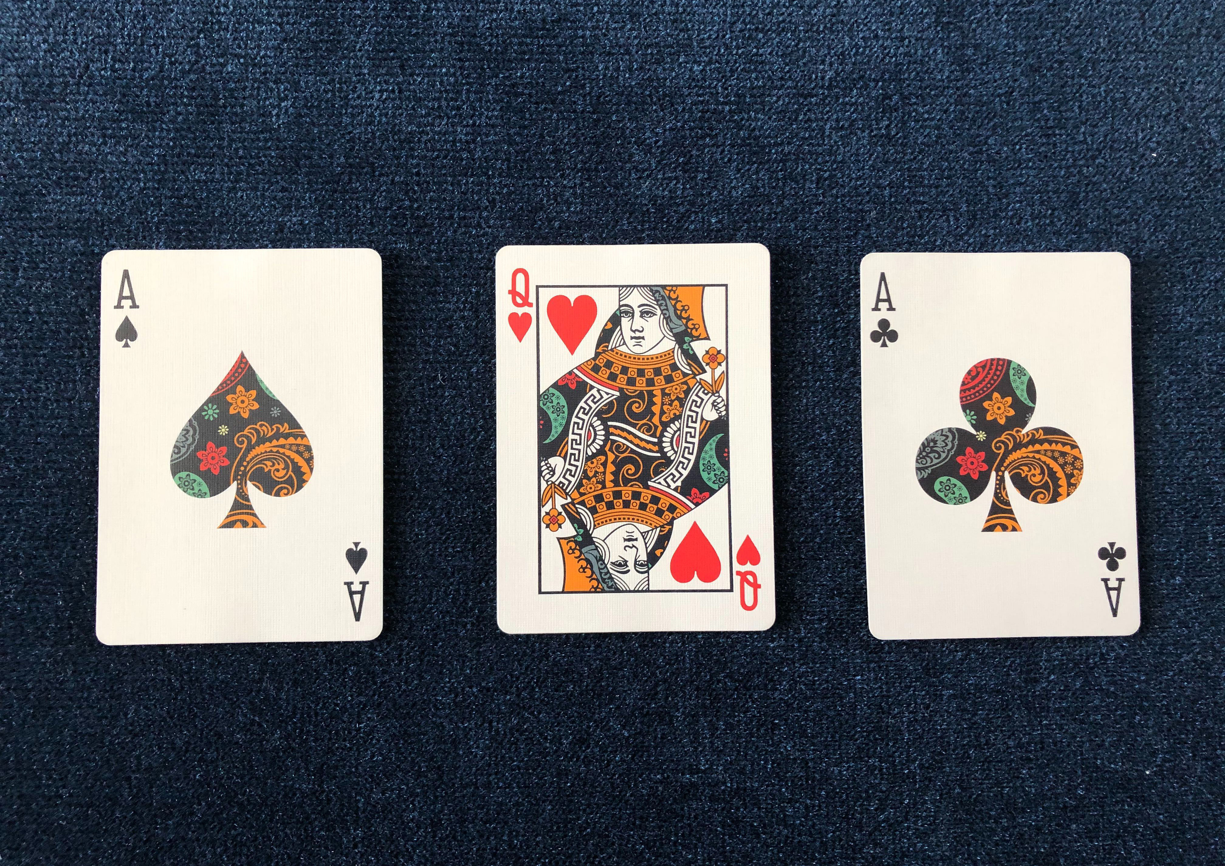 The Ace of Spades, Queen of Hearts and Ace of Clubs from the Dapper Deck Playing Cards are used on a blue close-up mat for an easy card trick