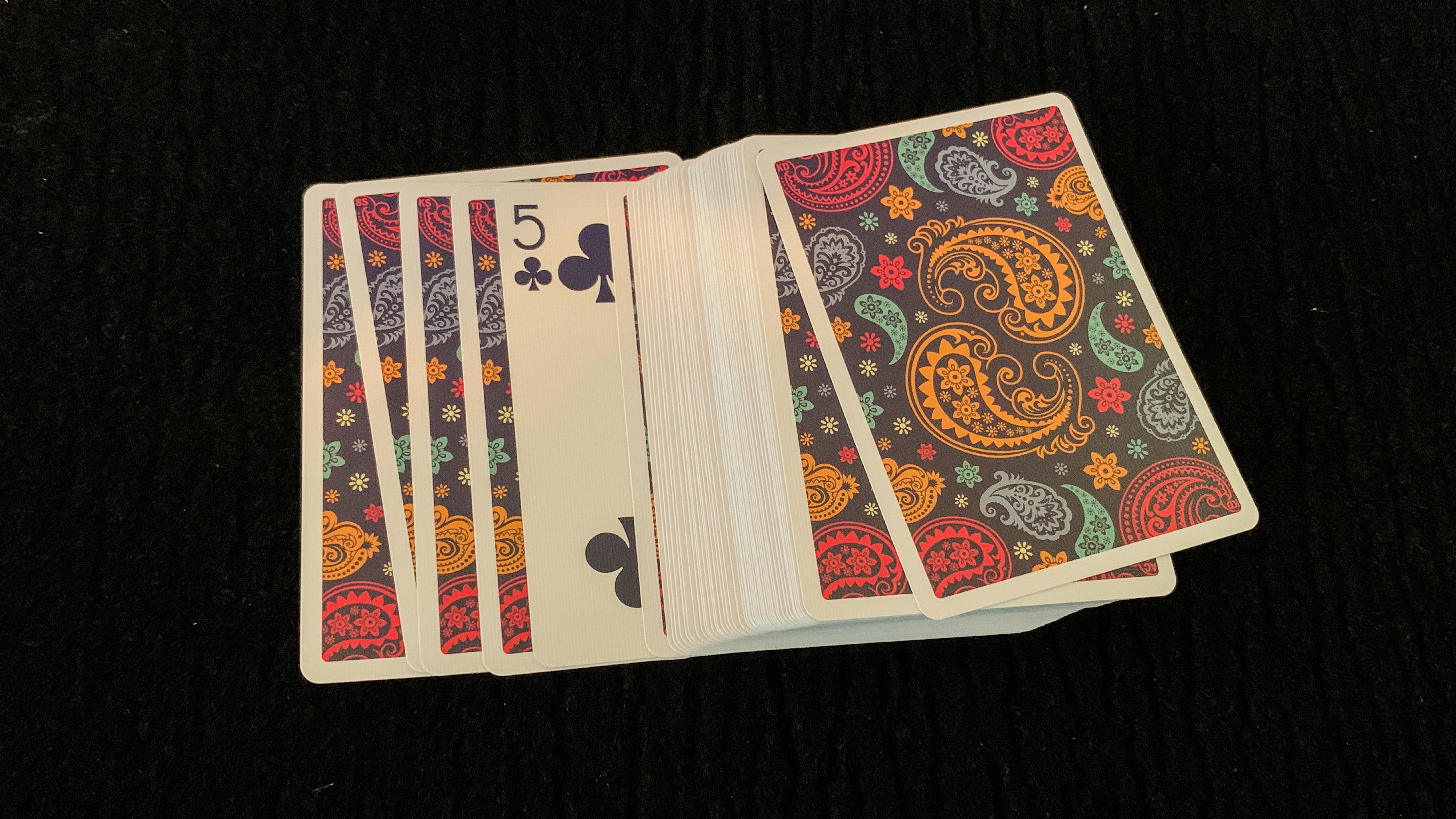 5 of Clubs peeks out of a face down card spread of dapper deck playing cards