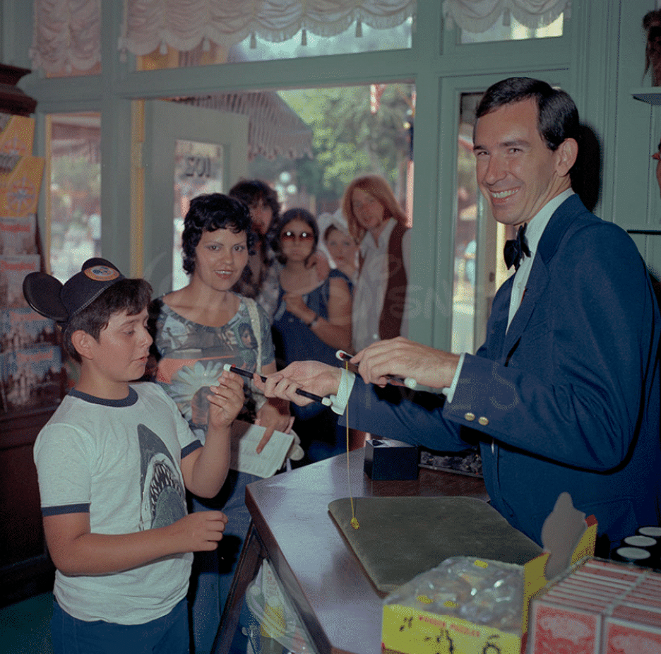 vintage photo of a magician performing magic trick for guest at disneyland magic shop
