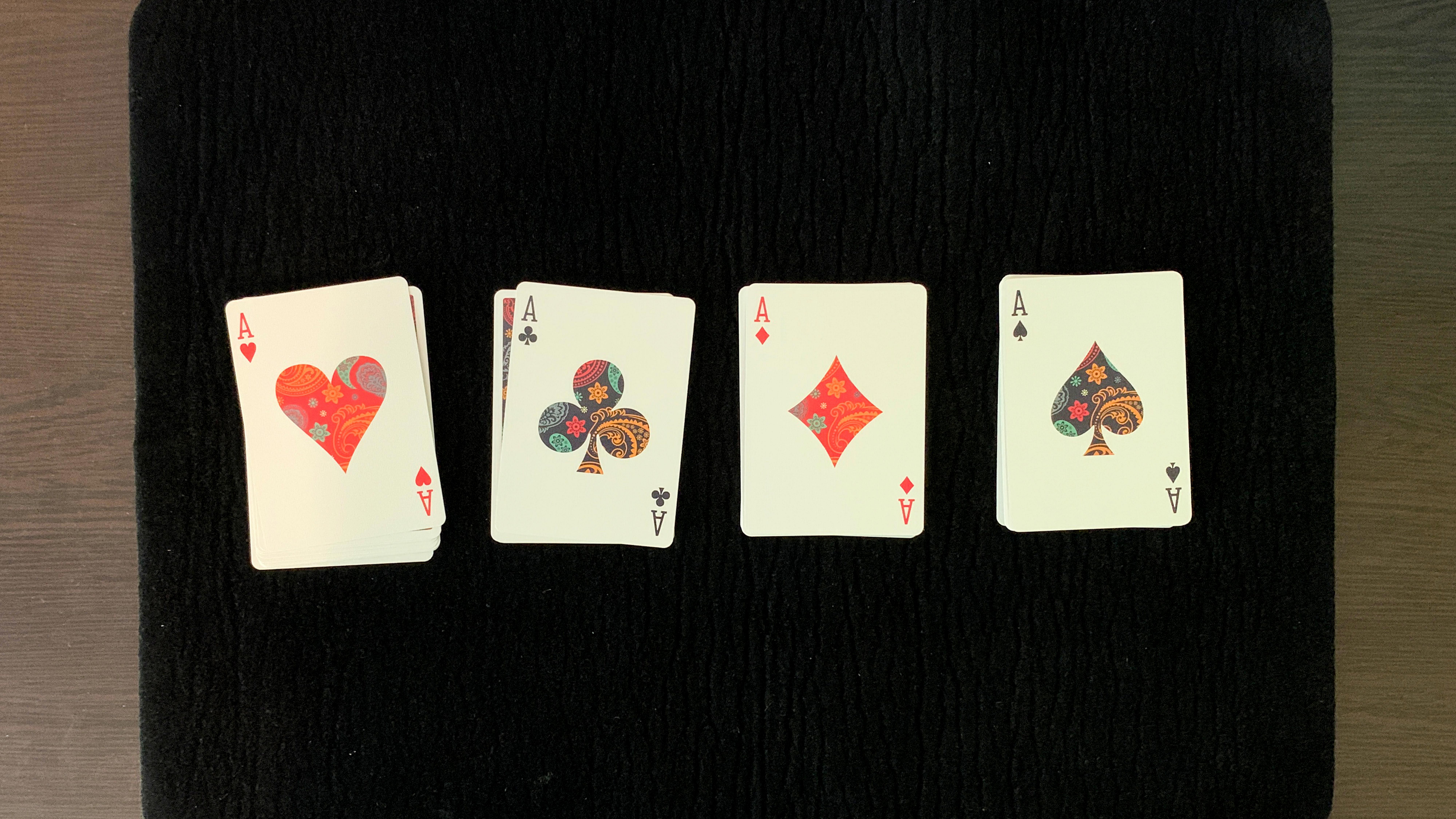 The four aces appear on the tops of four piles of playing cards during a poker magic trick