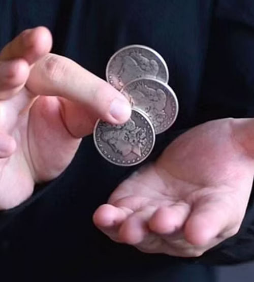 magician holds three coins