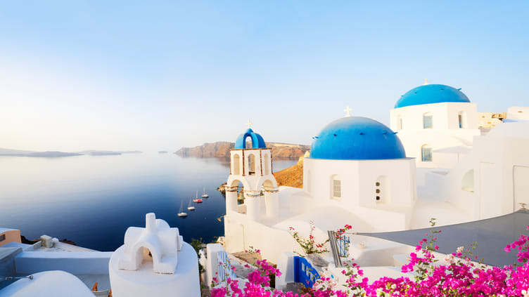 Classic Santorini white-washed buildings with blue domes overlooking the sea
